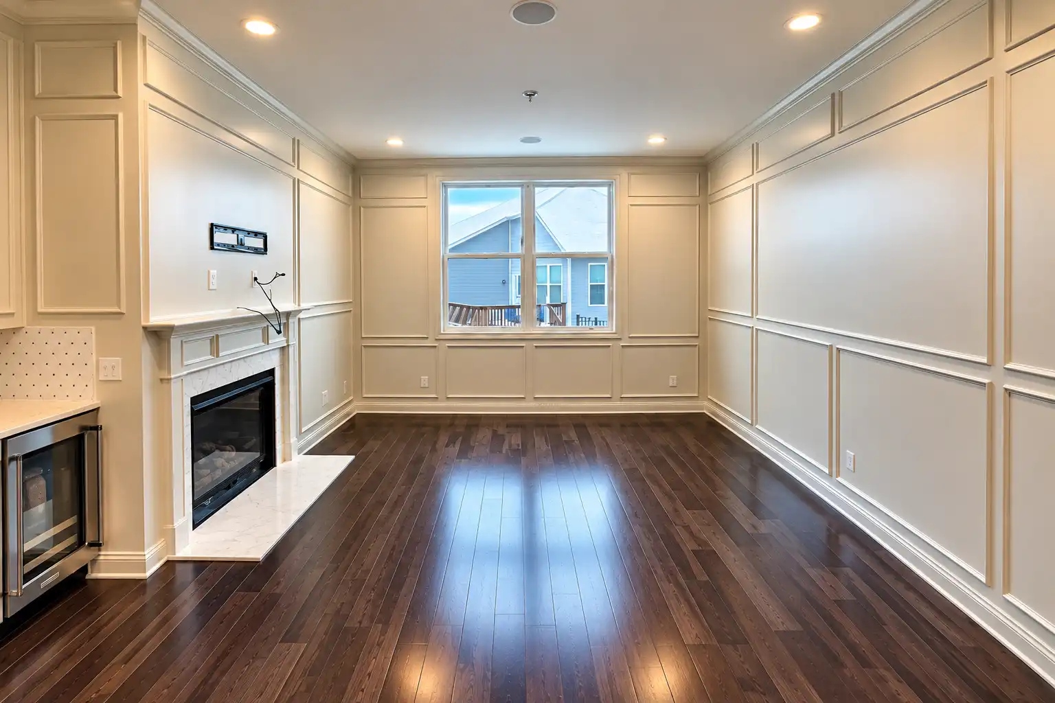Living room with floor-to-ceiling picture frame moulding painted cream, fireplace, and dark hardwood floors