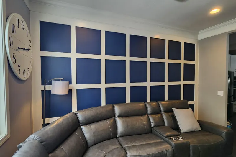 Left-angle view of navy and white judge's paneling wall, Sherwin-Williams Naval (SW 6244) boxes with Pure White (SW 7005) trim, wall clock and floor lamp