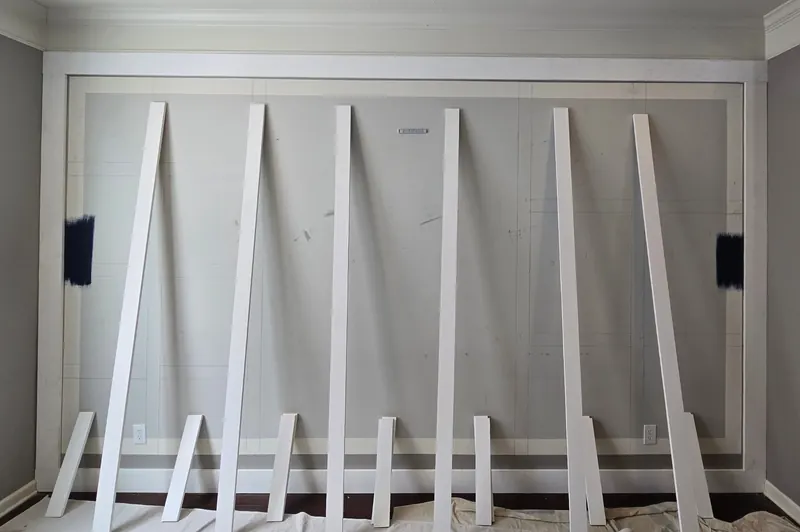 Primed white boards leaning against the wall during judge's paneling installation, with the new outer frame in place