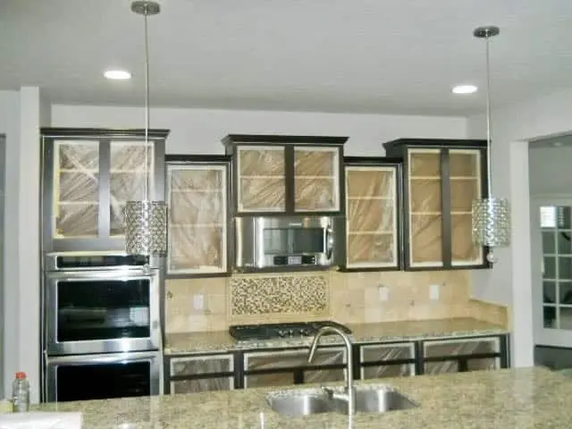 Wood kitchen cabinets with counters and floors covered in paper and plastic, ready for painting