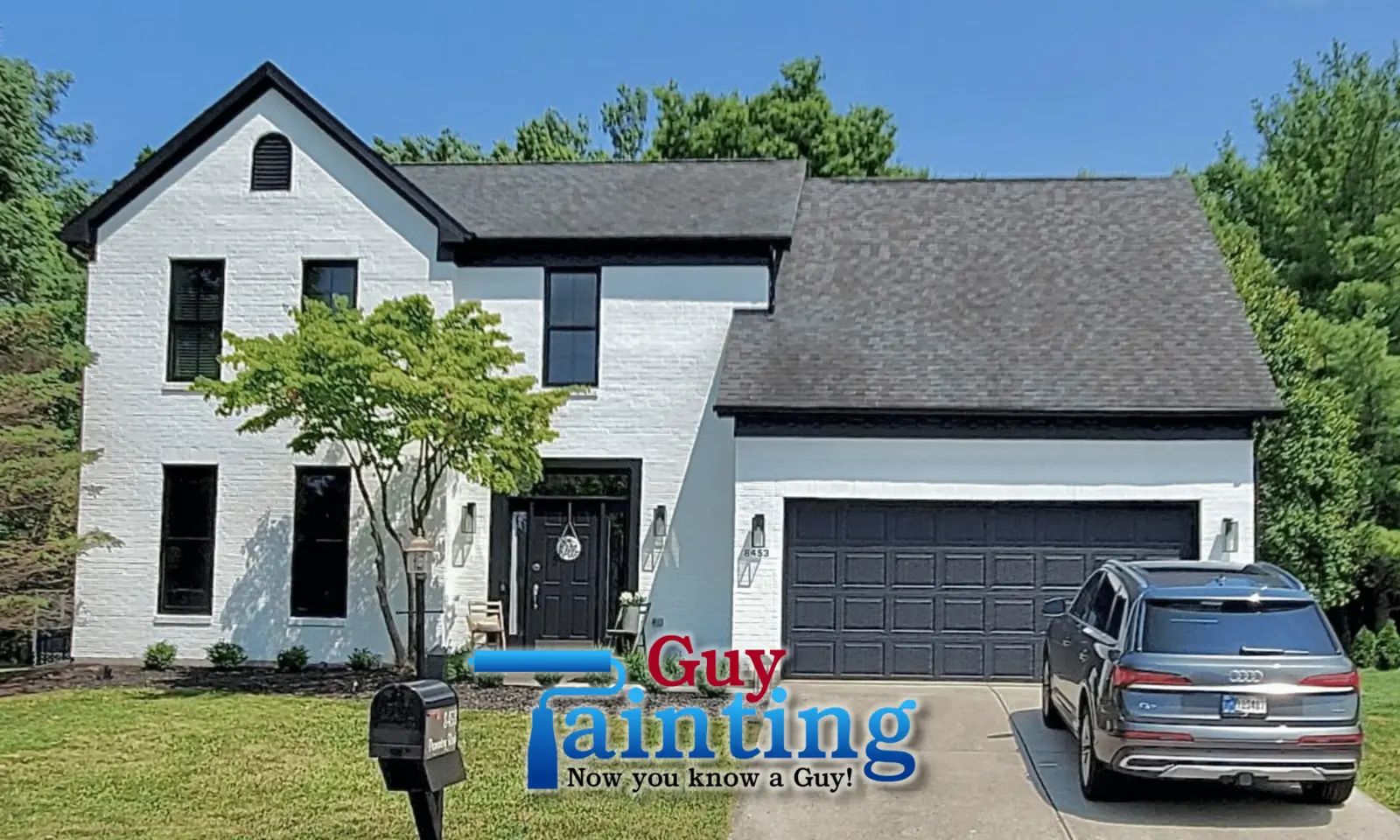 Farmhouse-style home with brick and siding painted white, black trim and a black garage door