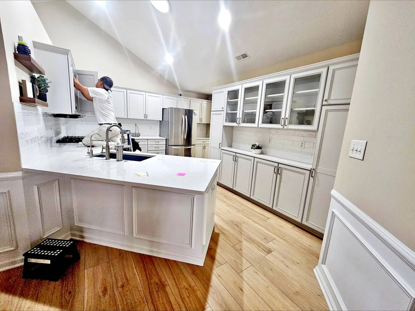 Painter installing hardware on oak kitchen cabinets newly painted white