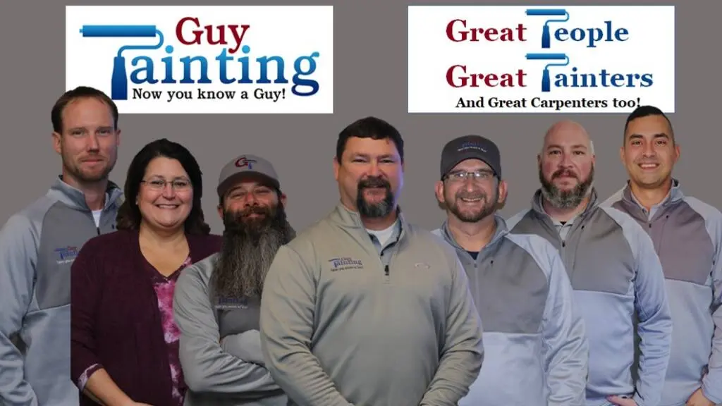 Seven Guy Painting crew members in gray company pullovers under a "Great People, Great Painters" banner
