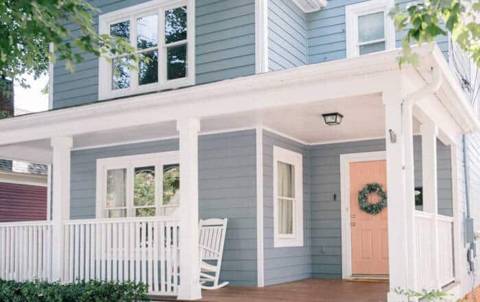 Two-story home with light blue siding, white trim, and a peach-colored front door.