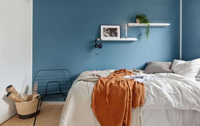 Bedroom with a smooth deep blue accent wall complementing light bedding and minimalist decor.